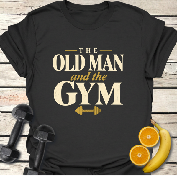 Old Man and the Gym T-Shirt displayed with dumbbells and fruits on a wooden surface.